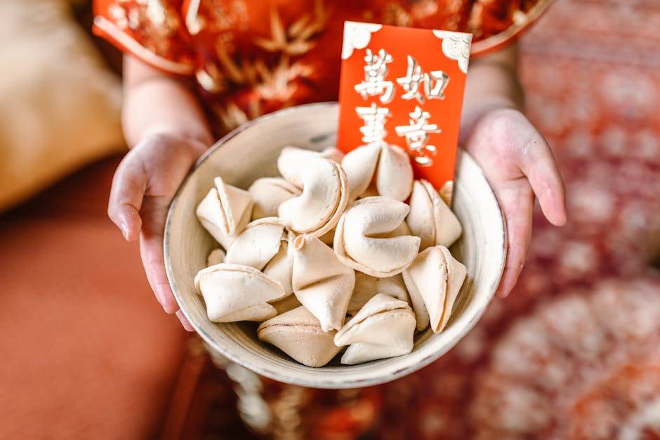 量子與吸引力法則 A set of fortune cookies in a bowl held by hands, accompanied by a red envelope, symbolizes Chinese New Year celebrations.